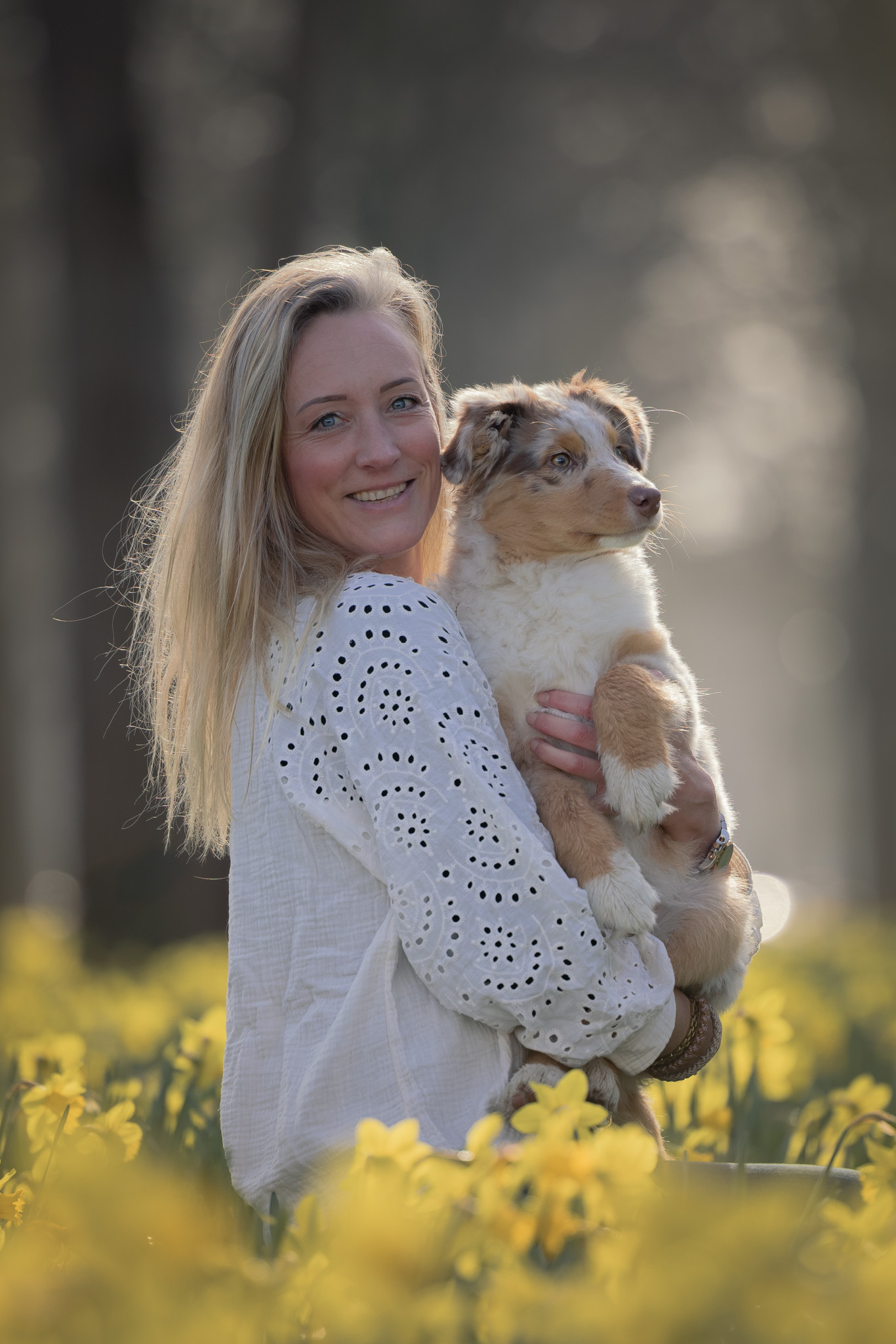 Mirna met haar hond op de arm tussen de gele narcissen